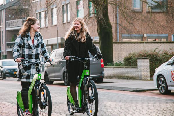 Photo showing two people cycling on electric bike in a city