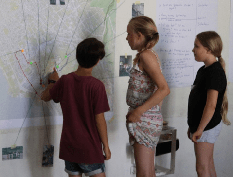 Three children pointing to a map, participating in a neighbourhood mobility workshop
