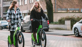 Photo showing two people cycling on electric bike in a city