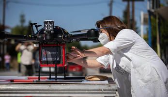 A woman adjusts a drone with the Harmony logo before take-off. 