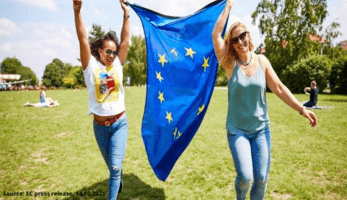 Two young people in the sun holding up the EU flag